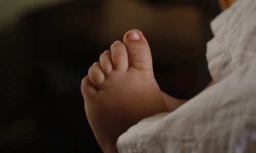 a close up of a baby's foot on a bed