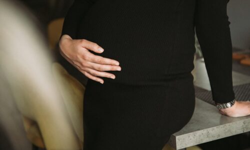 a pregnant woman standing on a stool with her hands on her stomach