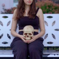 woman holding skull sitting on bench