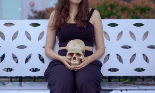 woman holding skull sitting on bench