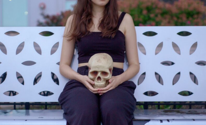woman holding skull sitting on bench