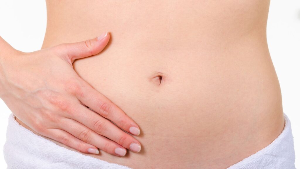 女性が両手でお腹を優しく包んでいる様子 タイトル: 産後の下っ腹ぽっこり解消法