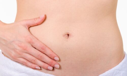 女性が両手でお腹を優しく包んでいる様子 タイトル: 産後の下っ腹ぽっこり解消法