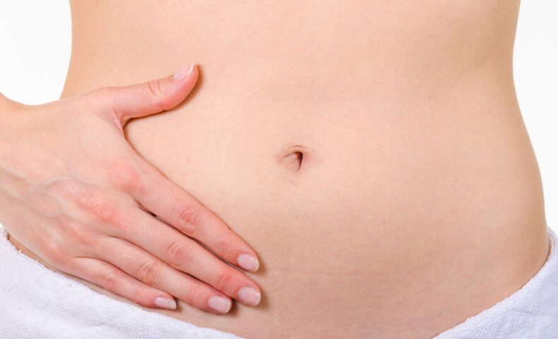女性が両手でお腹を優しく包んでいる様子 タイトル: 産後の下っ腹ぽっこり解消法