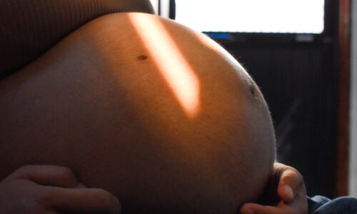 Pregnant woman's belly illuminated by sunlight.