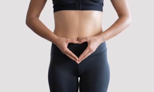 黒いスポーツウェアを着た女性がお腹の前でハートの形を作っている様子